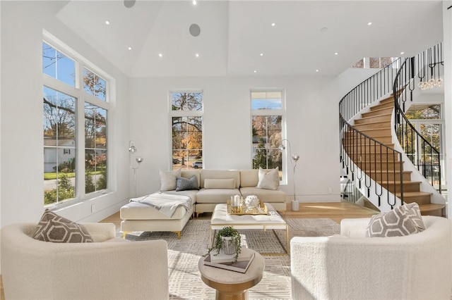 living room with a healthy amount of sunlight, a high ceiling, and light hardwood / wood-style floors