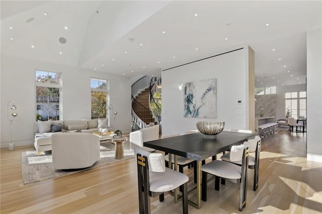 dining area featuring a wealth of natural light, a towering ceiling, and light hardwood / wood-style floors