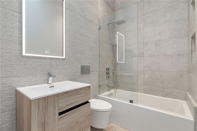 full bathroom with vanity, tiled shower / bath combo, toilet, and tile walls