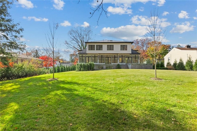 back of property with a sunroom and a lawn