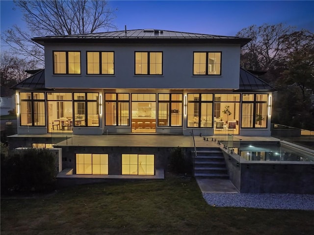 back house at dusk featuring a patio and a swimming pool