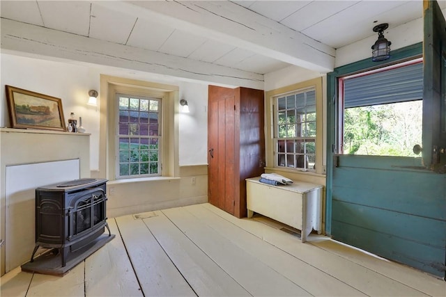 interior space with beamed ceiling, hardwood / wood-style floors, and a wood stove
