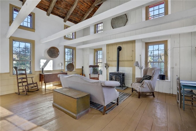 living room with beamed ceiling, a wood stove, high vaulted ceiling, and wooden ceiling