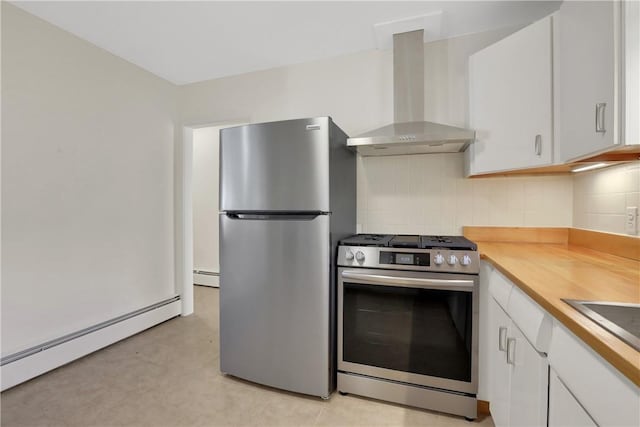 kitchen with white cabinets, wall chimney exhaust hood, decorative backsplash, baseboard heating, and appliances with stainless steel finishes
