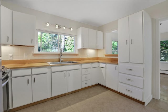 kitchen featuring backsplash, sink, butcher block countertops, white cabinetry, and stainless steel electric range