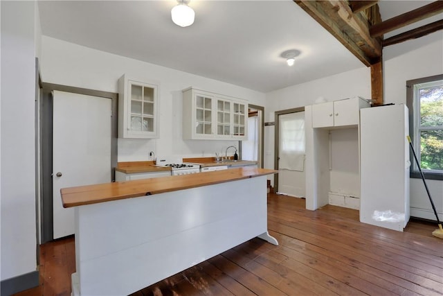 kitchen with butcher block counters, sink, dark hardwood / wood-style floors, kitchen peninsula, and white cabinets