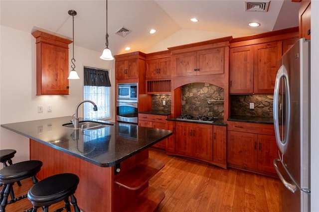 kitchen with pendant lighting, a kitchen breakfast bar, sink, light wood-type flooring, and stainless steel appliances