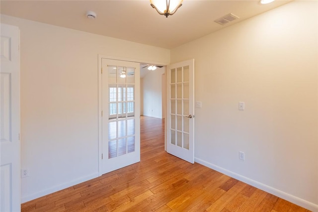 spare room featuring french doors and light wood-type flooring