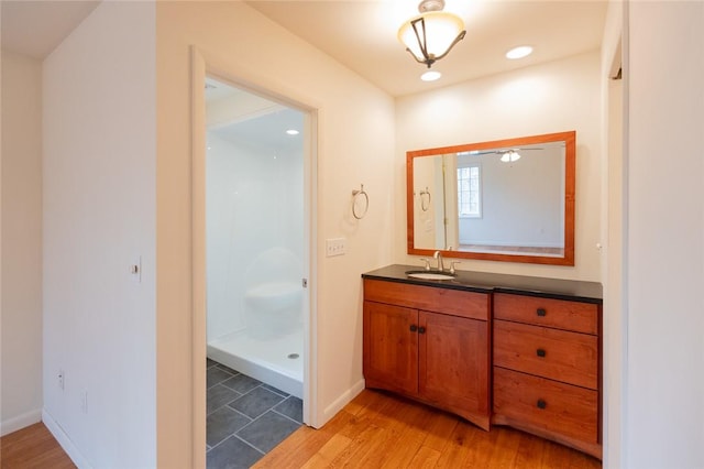 bathroom with hardwood / wood-style flooring, vanity, and a shower