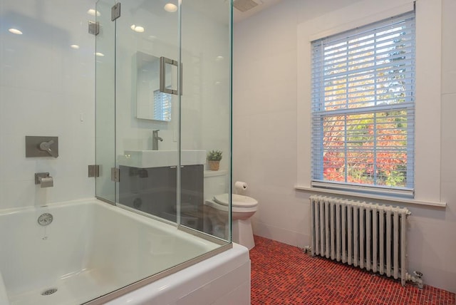 bathroom featuring combined bath / shower with glass door, toilet, and radiator