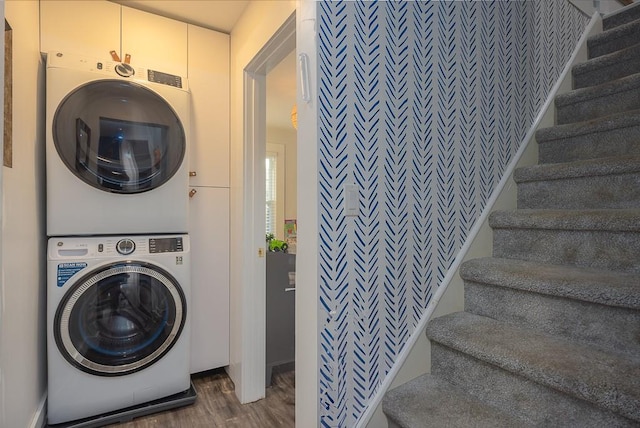 clothes washing area with cabinets, dark hardwood / wood-style floors, and stacked washer and clothes dryer