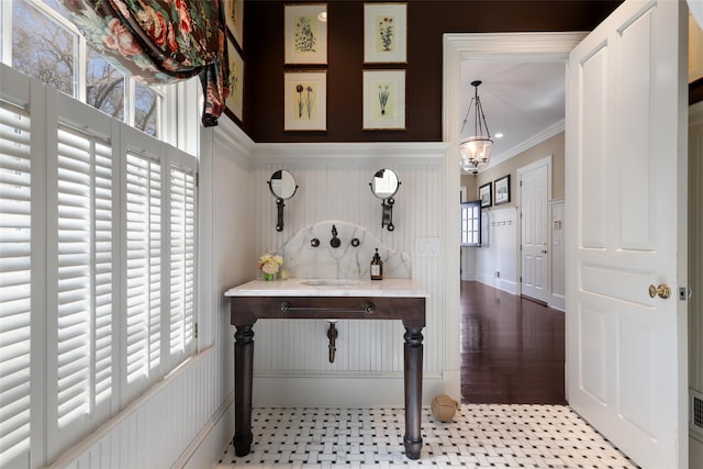 office area featuring an inviting chandelier, a decorative wall, ornamental molding, and wainscoting