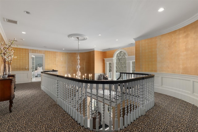 corridor featuring dark carpet, recessed lighting, ornamental molding, and a decorative wall