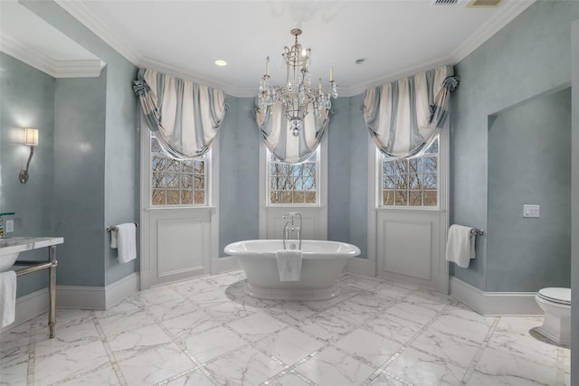 bathroom featuring baseboards, ornamental molding, a freestanding tub, and a chandelier