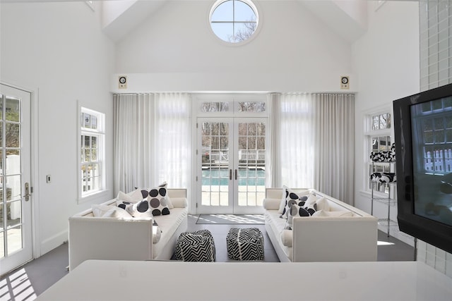 living area featuring plenty of natural light, high vaulted ceiling, and french doors