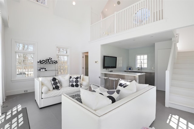 living room with stairway, a high ceiling, and plenty of natural light