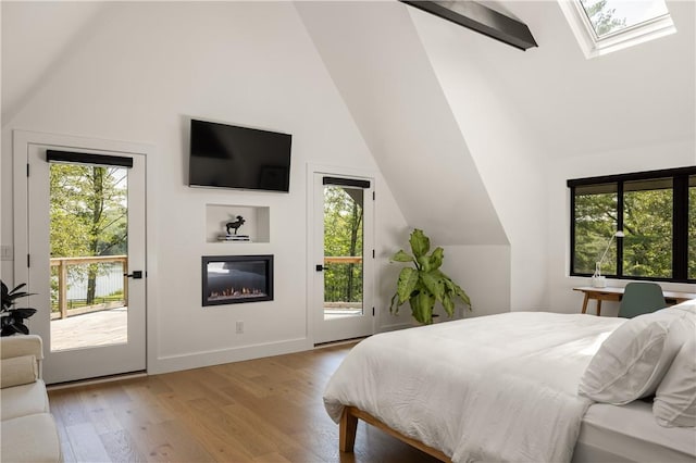 bedroom with access to outside, vaulted ceiling with skylight, and light wood-type flooring