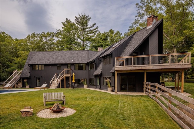 back of property featuring a lawn, a fire pit, and a deck