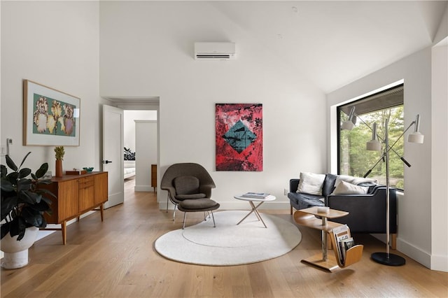 sitting room with wood-type flooring, high vaulted ceiling, and an AC wall unit