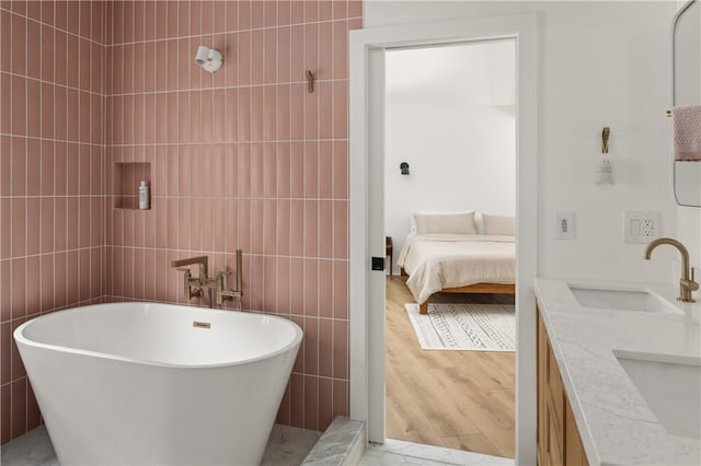 bathroom with vanity, wood-type flooring, a tub, and tile walls