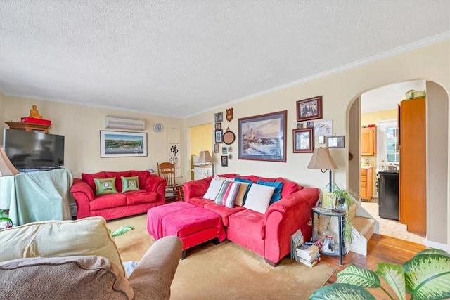 carpeted living room with ornamental molding, a textured ceiling, and a wall unit AC