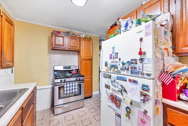 kitchen with sink, tasteful backsplash, white refrigerator, stainless steel range with gas stovetop, and ornamental molding