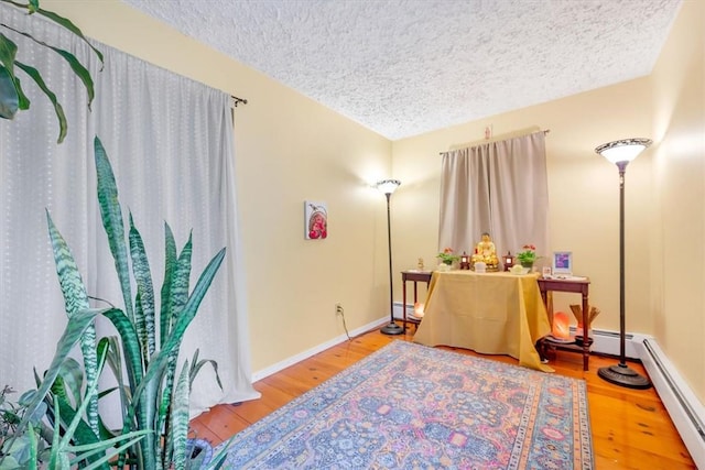 interior space with wood-type flooring, a textured ceiling, and baseboard heating