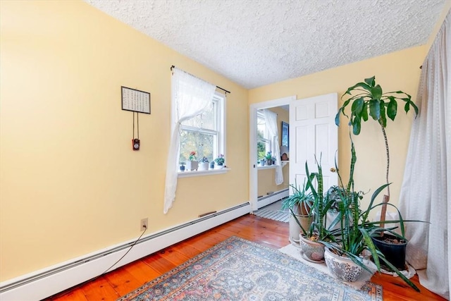 living area with light hardwood / wood-style floors, a textured ceiling, and a baseboard radiator