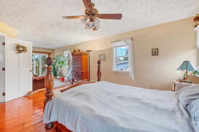 bedroom with ceiling fan, wood-type flooring, a textured ceiling, and multiple windows