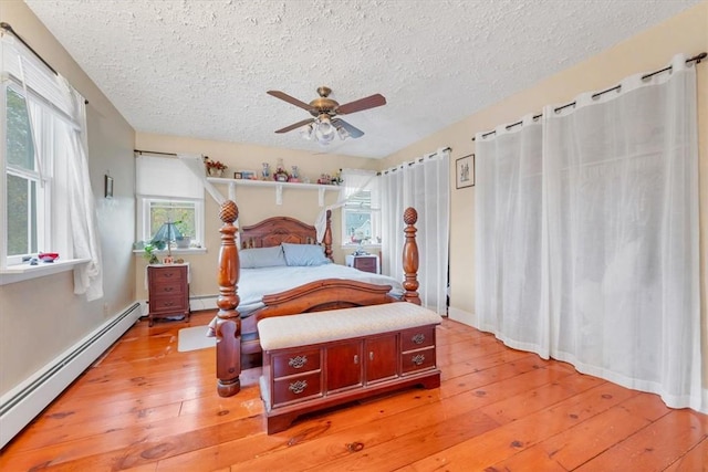 bedroom with multiple windows, ceiling fan, light hardwood / wood-style floors, and a baseboard heating unit