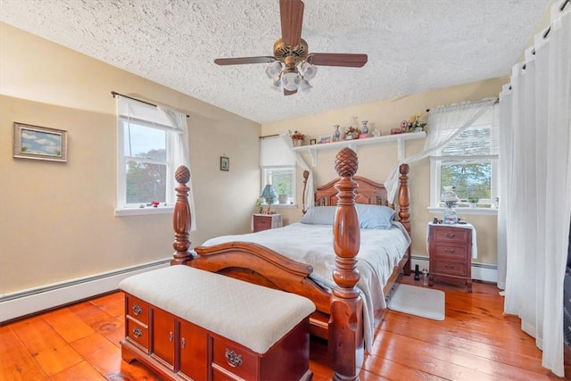 bedroom with ceiling fan, hardwood / wood-style floors, a textured ceiling, and a baseboard heating unit