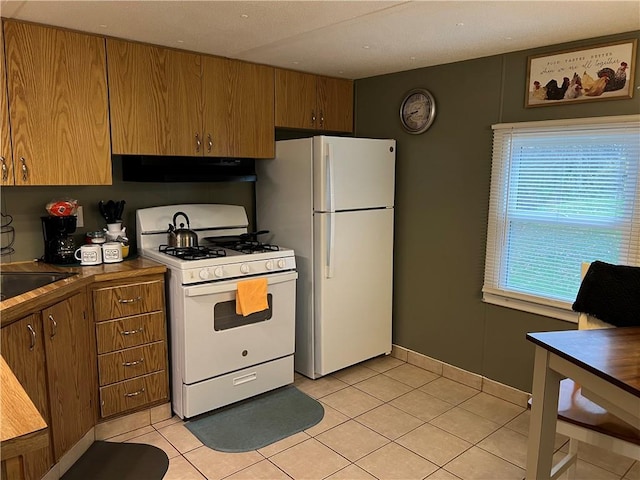 kitchen with range hood, light tile patterned floors, white appliances, and sink