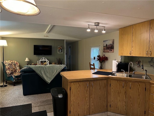 kitchen featuring sink, light colored carpet, and lofted ceiling with beams