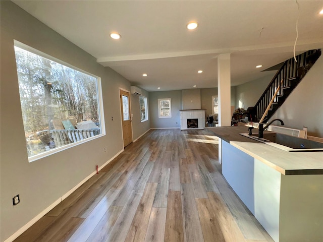 interior space featuring a fireplace, light hardwood / wood-style flooring, and a wall mounted air conditioner