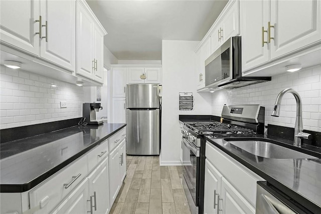 kitchen featuring sink, tasteful backsplash, light hardwood / wood-style flooring, white cabinets, and appliances with stainless steel finishes