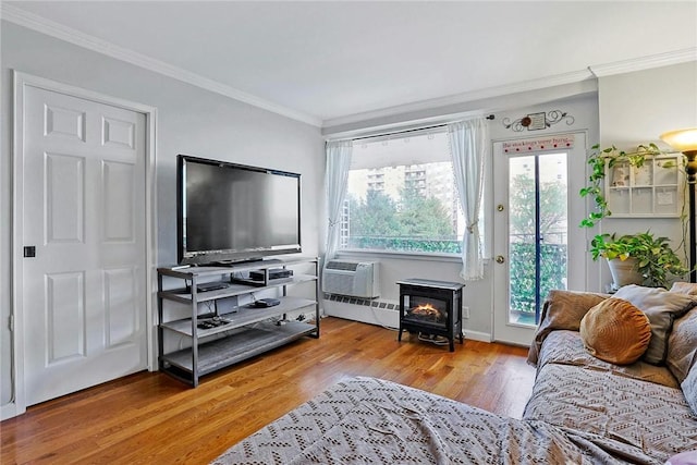 living room with wood-type flooring, ornamental molding, a baseboard radiator, and a wood stove