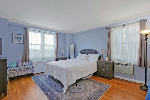 bedroom with a wall mounted air conditioner, crown molding, and light hardwood / wood-style flooring