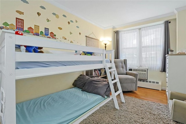 bedroom with baseboard heating, an AC wall unit, ornamental molding, and hardwood / wood-style flooring