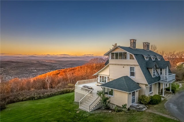 back house at dusk with a yard and a deck with mountain view