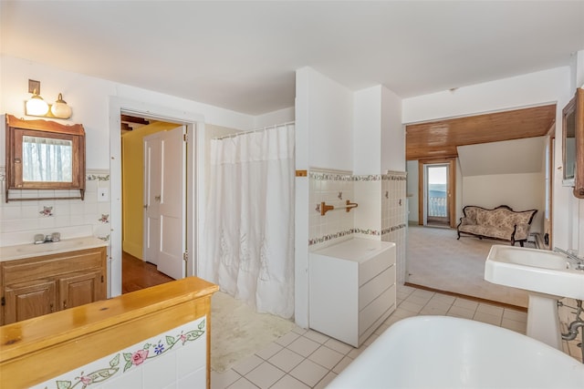 bathroom with a washtub, tile patterned floors, tile walls, and sink