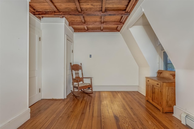 additional living space with beam ceiling, light wood-type flooring, a baseboard radiator, and wooden ceiling