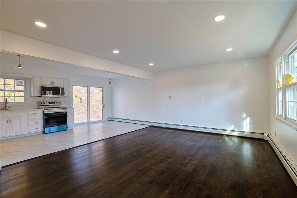 unfurnished living room with sink, light hardwood / wood-style floors, and a baseboard radiator