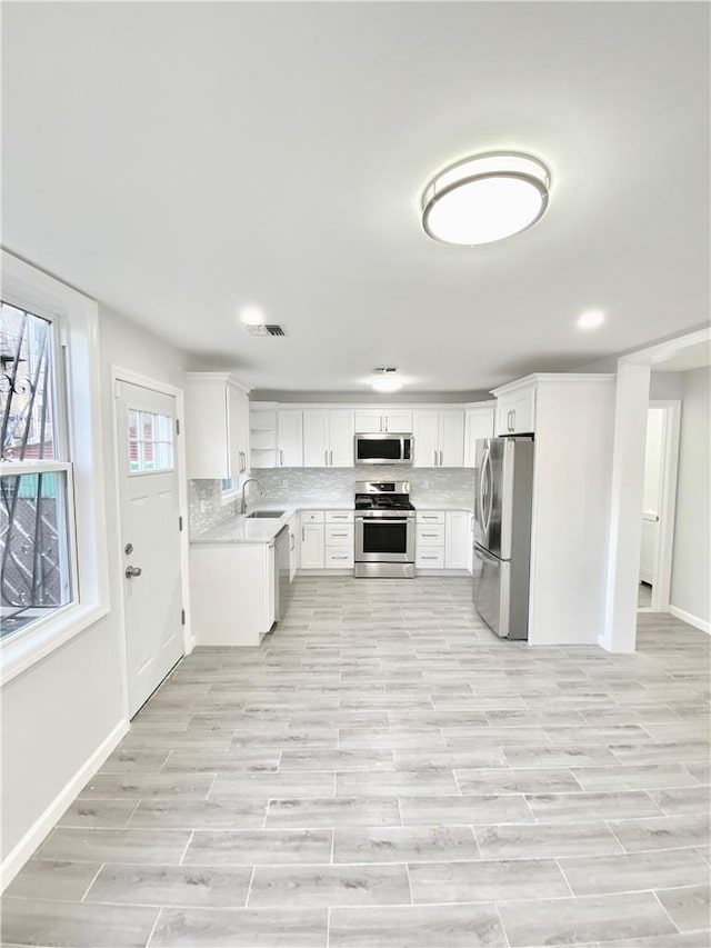 kitchen with white cabinets, light wood-type flooring, and stainless steel appliances