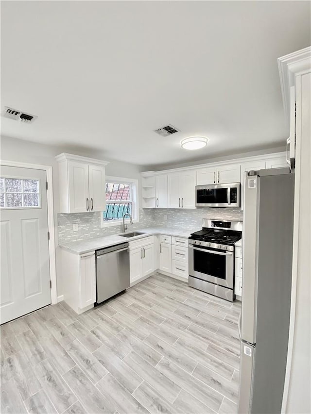 kitchen featuring visible vents, stainless steel appliances, light countertops, white cabinetry, and open shelves