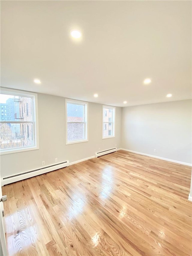 empty room with baseboard heating, recessed lighting, and light wood-style floors