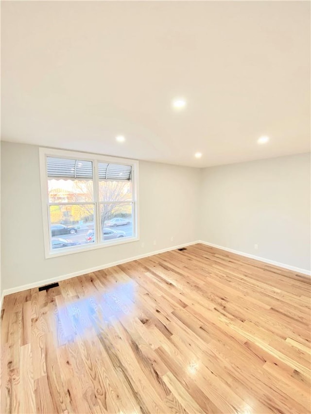 empty room with baseboards, recessed lighting, and light wood-style floors