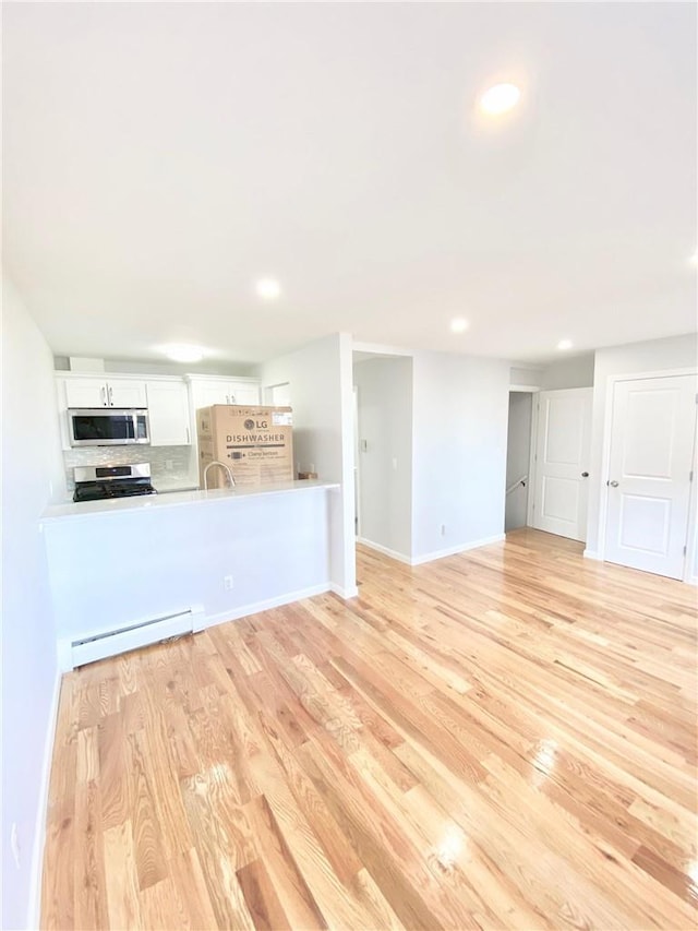 unfurnished living room with a baseboard heating unit, light wood-type flooring, baseboards, and recessed lighting