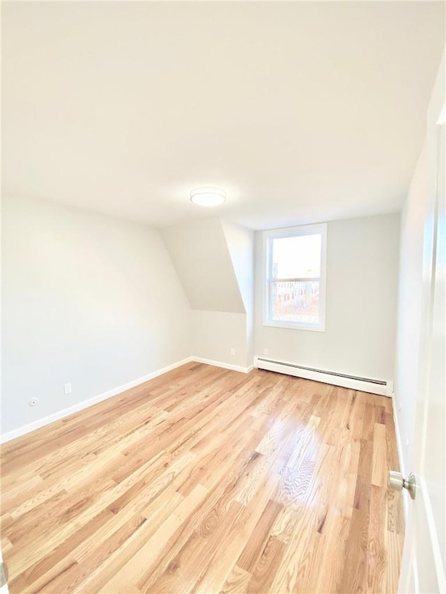 bonus room featuring lofted ceiling, light hardwood / wood-style floors, and a baseboard heating unit