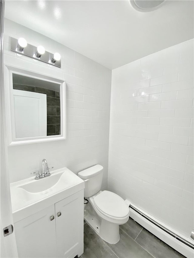 half bathroom featuring a baseboard radiator, toilet, tile walls, vanity, and tile patterned floors