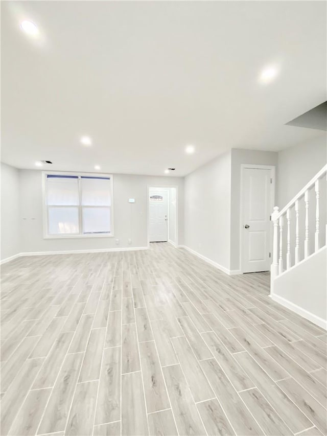 interior space with light wood-type flooring, baseboards, and stairs